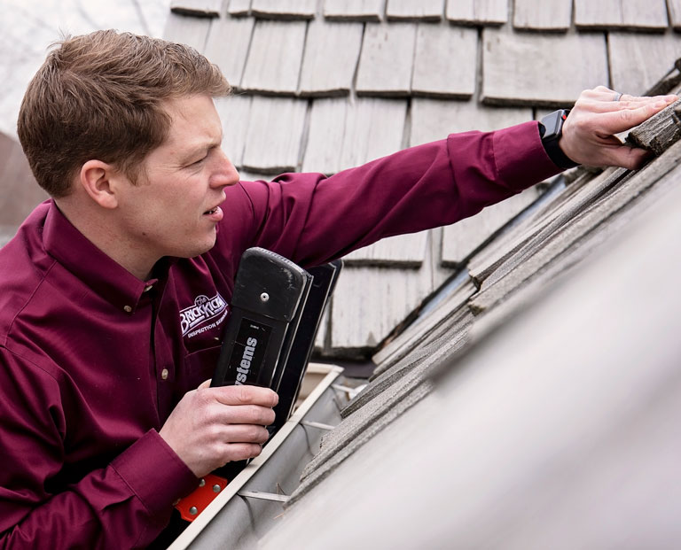 An inspector from The BrickKicker reviewing a roof